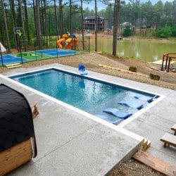 Pool with in-water loungers, court and pond beyond