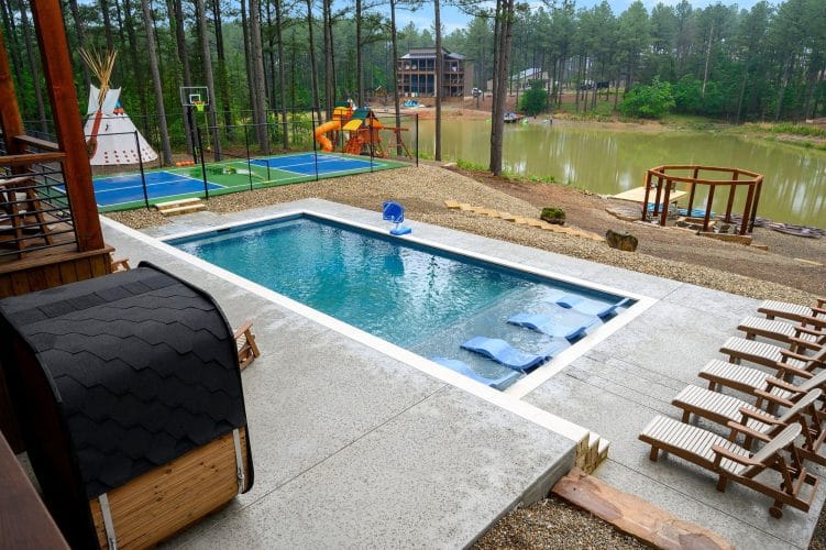 Pool with in-water loungers, court and pond beyond