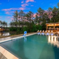 Pool with a covered gazebo and loungers beside the pond at dusk