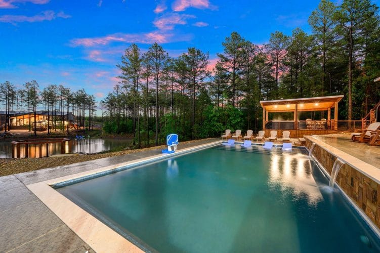 Pool with a covered gazebo and loungers beside the pond at dusk