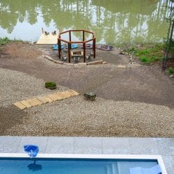 Aerial of the pond shore with a fire pit gazebo and the pool below