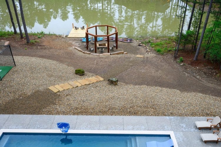 Aerial of the pond shore with a fire pit gazebo and the pool below