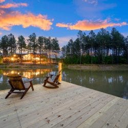 Wood dock with two Adirondack chairs on the pond at dusk