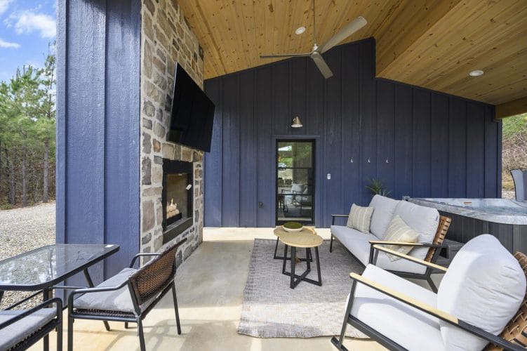 Stone fireplace and TV on the covered patio with a sofa and small tables