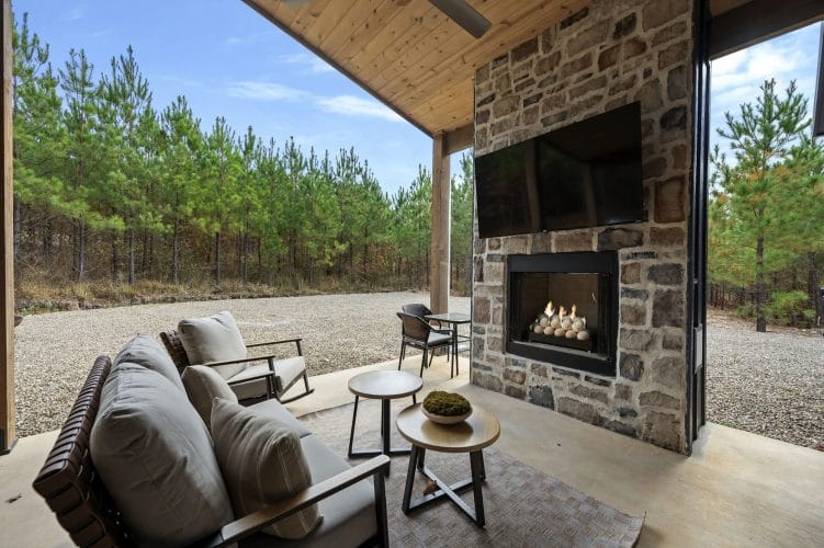 Outdoor sofa and chairs in front of the stone fireplace and TV on the patio