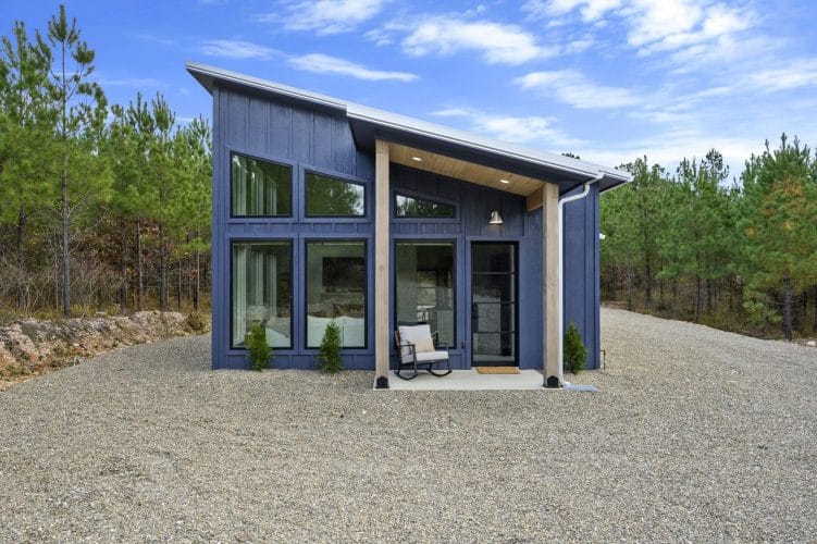 Front of the blue board-and-batten cabin with a slanted metal roof and big windows