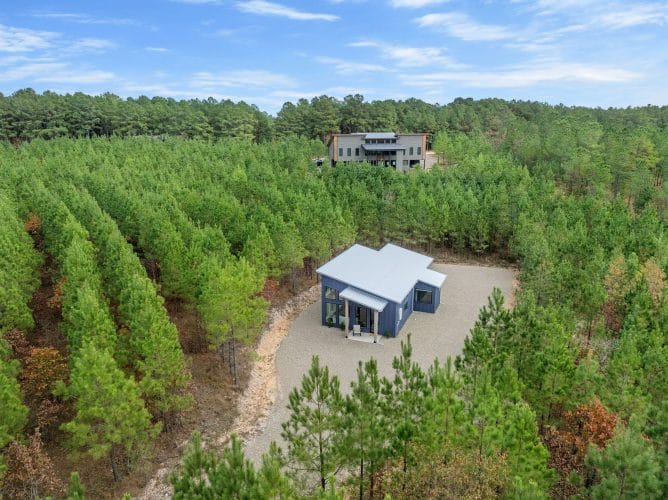 Aerial of the cabin in the pines with another house visible on the ridge