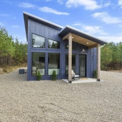 Front of the cabin with covered entry and gravel driveway under blue sky