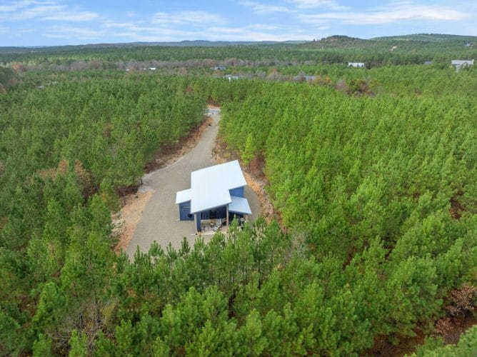 Aerial view of the cabin and gravel drive in a forest of young pines