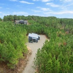 Aerial of the cabin with a larger house visible far behind it in the trees