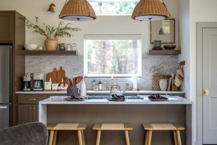 Kitchen island with three wood stools, rattan pendant lights and a window over the sink