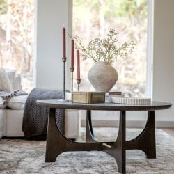Sofa and round wood coffee table in front of a tall window