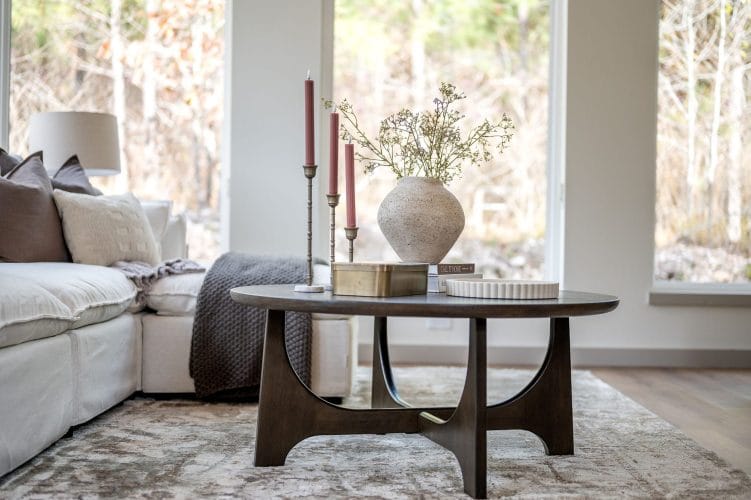 Sofa and round wood coffee table in front of a tall window
