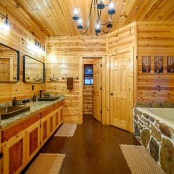 Bathroom with a double granite vanity and a stone-surround tub