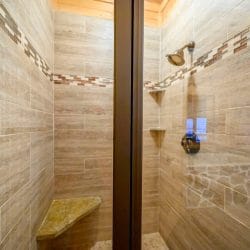 Tile walk-in shower with a stone bench and a glass door