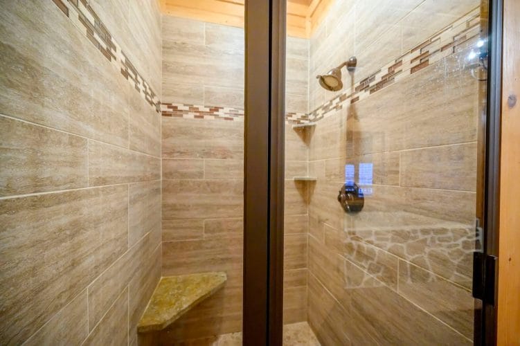 Tile walk-in shower with a stone bench and a glass door