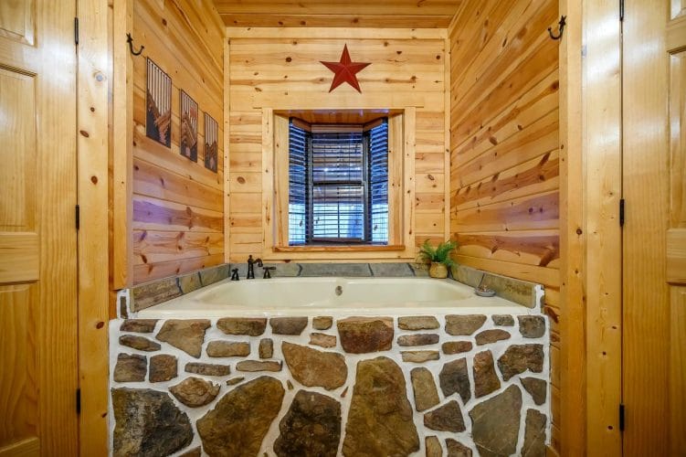 Soaking tub with a fieldstone surround under a window