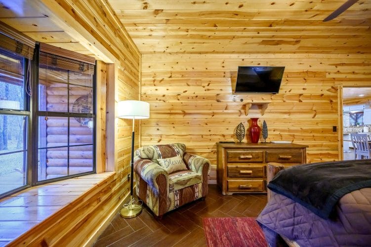 Bedroom with an armchair, dresser, floor lamp and wall TV