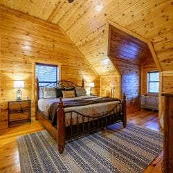 Upstairs bedroom with a black iron-and-wood bed, striped rug and a sloped ceiling