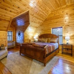 Upstairs bedroom with a carved wood bed, red southwestern bedding and a portable crib in the corner