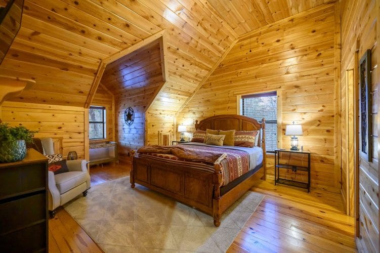 Upstairs bedroom with a carved wood bed, red southwestern bedding and a portable crib in the corner