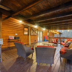 Covered deck seating with wicker chairs and a desk-height counter along the log wall