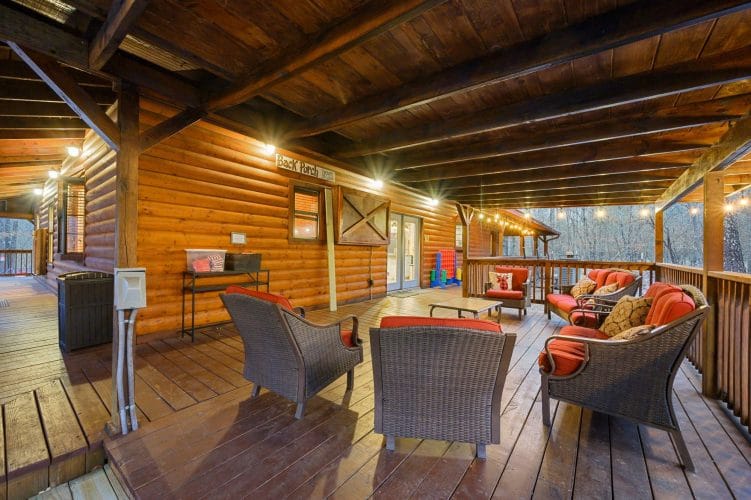 Covered deck seating with wicker chairs and a desk-height counter along the log wall