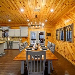 Long wood dining table with chairs under a wagon-wheel chandelier, set for a meal