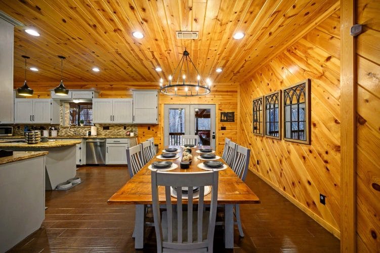 Long wood dining table with chairs under a wagon-wheel chandelier, set for a meal