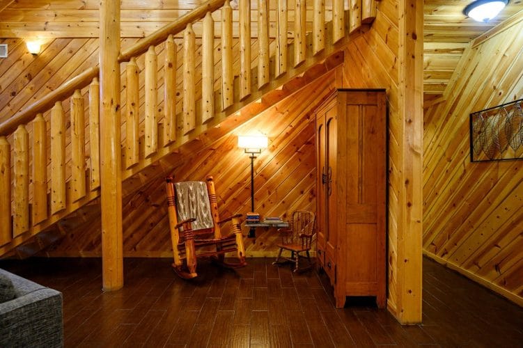 Staircase with a log railing, a rocking chair and a wooden armoire beneath it