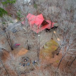 Aerial view of the red roof and yard through bare trees