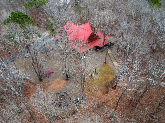 Aerial view of the red roof and yard through bare trees