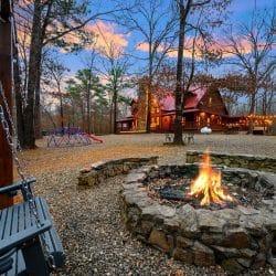 Burning stone fire pit with the play dome and cabin behind