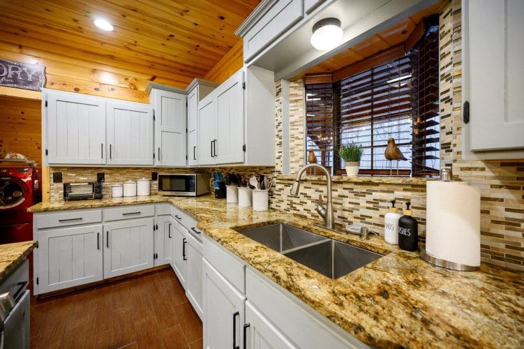 Double kitchen sink under a window with a tile backsplash