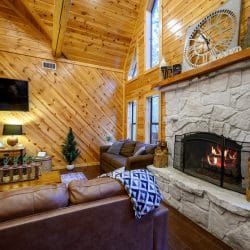 Floor-to-ceiling stone fireplace with a fire burning and leather sofa in front