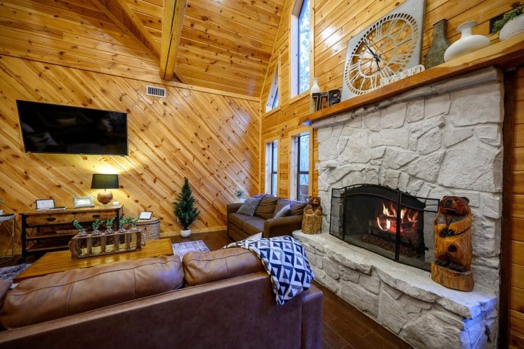 Floor-to-ceiling stone fireplace with a fire burning and leather sofa in front