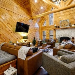 Living room seating facing the stone fireplace, with windows up the wall