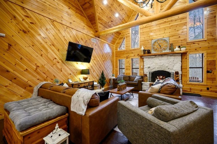 Living room seating facing the stone fireplace, with windows up the wall