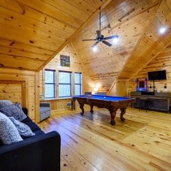 Loft with a pool table, sleeper sofa, an arcade cabinet, a TV and a row of windows