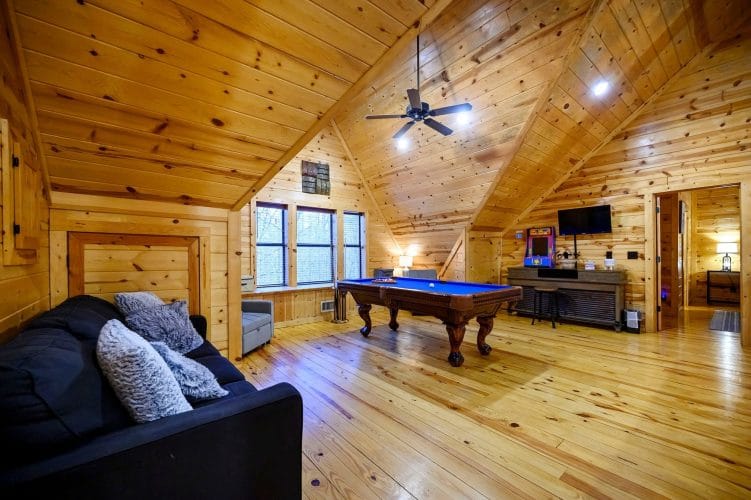 Loft with a pool table, sleeper sofa, an arcade cabinet, a TV and a row of windows