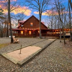 Horseshoe pit in the gravel yard with the cabin's lit porch behind it