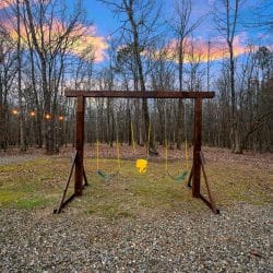 Wooden swing set with swings in the yard at dusk