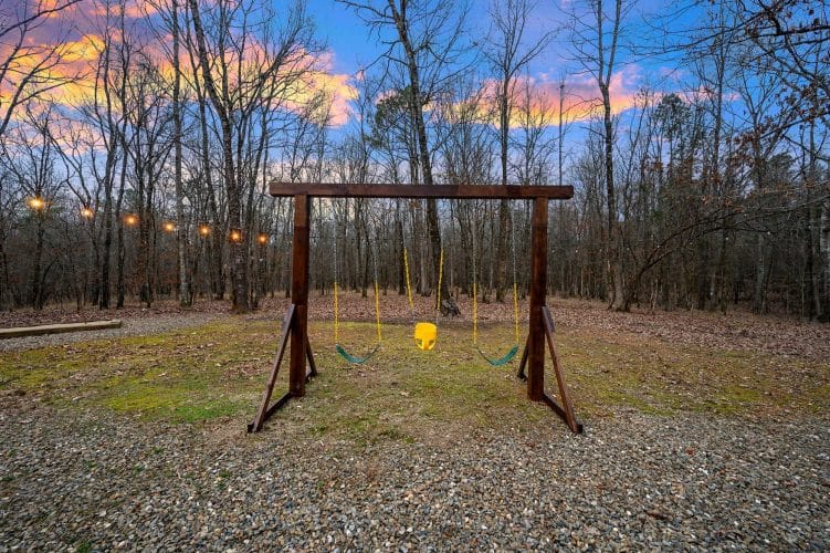 Wooden swing set with swings in the yard at dusk