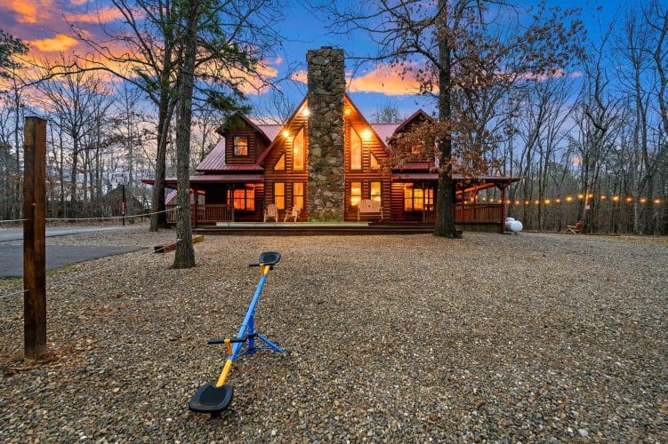 Seesaw in the gravel yard with the cabin's stone chimney in the background