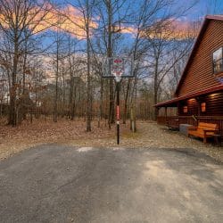 Basketball goal on the asphalt driveway beside the cabin porch