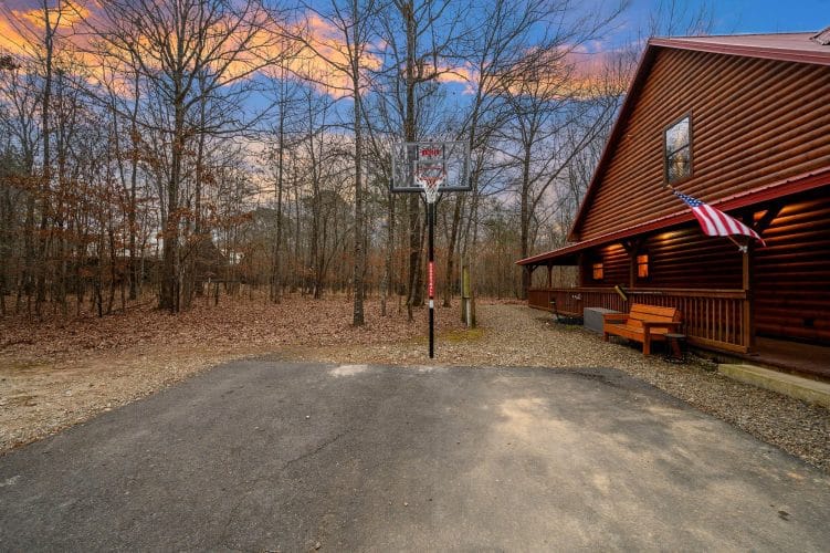 Basketball goal on the asphalt driveway beside the cabin porch