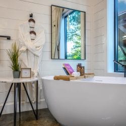 Freestanding tub beside a window with a robe, a towel and a small round side table