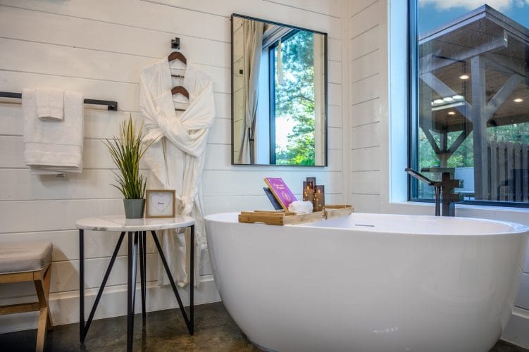 Freestanding tub beside a window with a robe, a towel and a small round side table