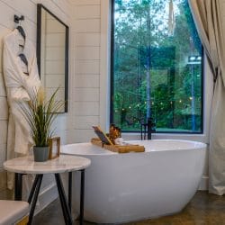 Freestanding tub beside a big window, with a robe and towels
