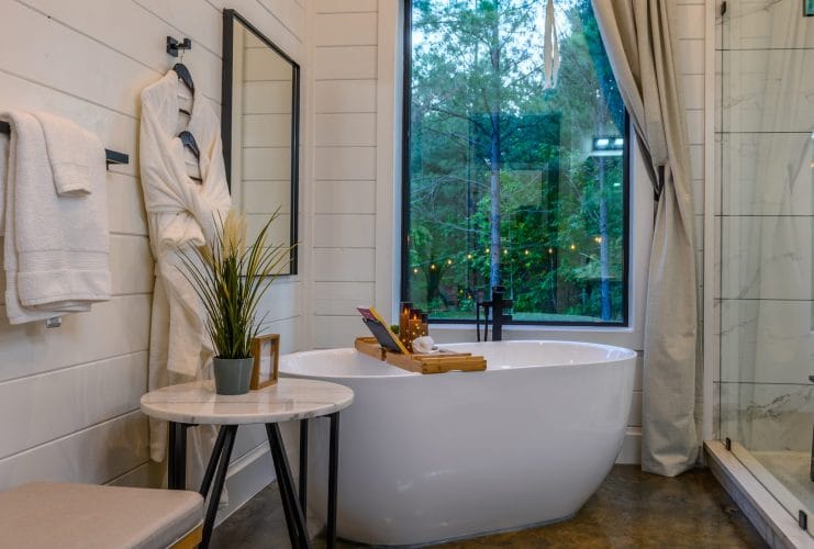 Freestanding tub beside a big window, with a robe and towels